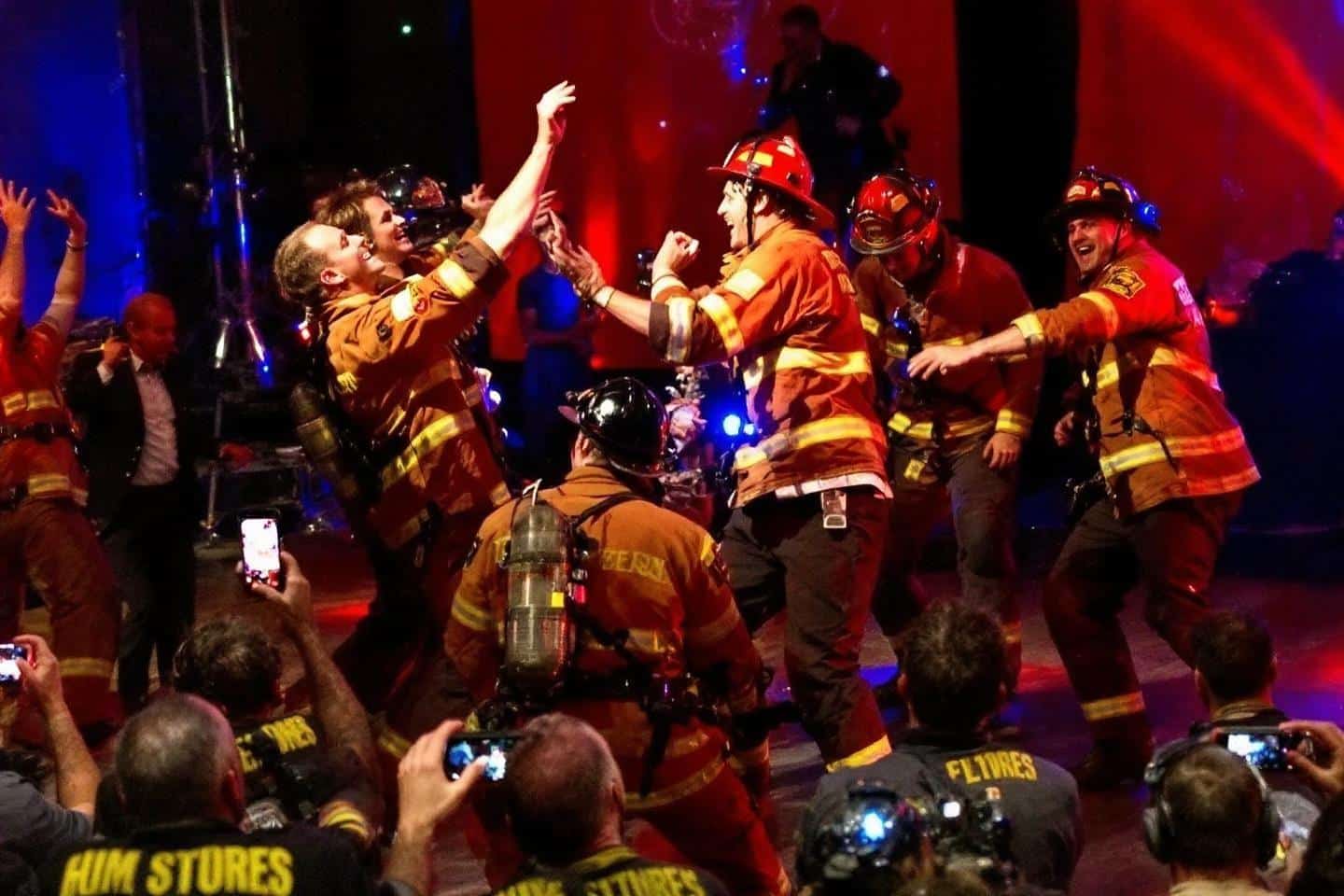 Groupe de pompiers en uniformes orange dansant et célébrant