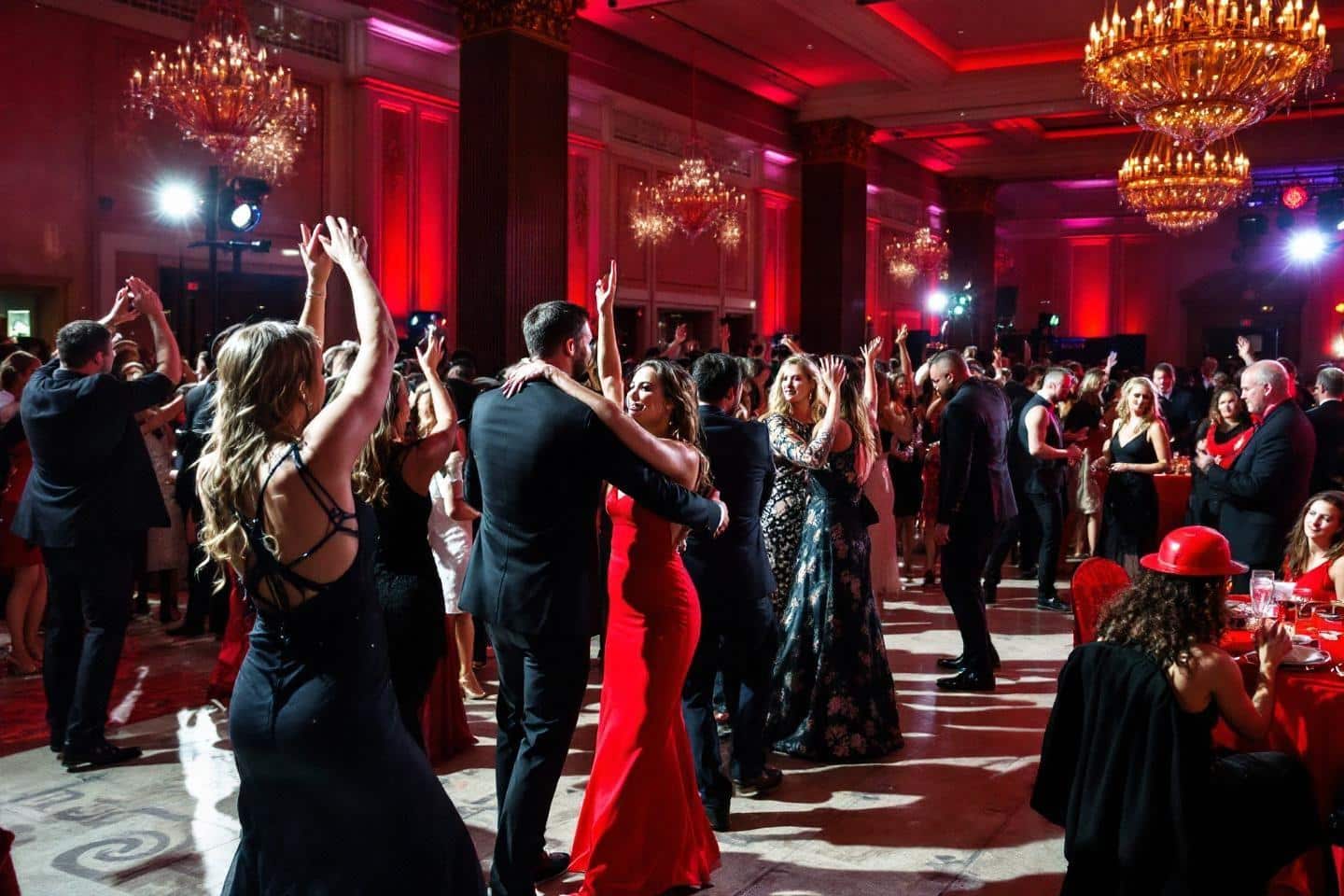 Grande salle de bal rouge avec des invités dansant